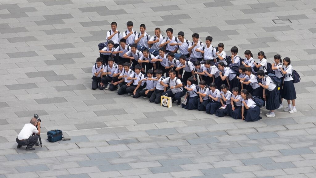 A photographer takes a picture of a class of students and their teacher, Tokyo station, Marunouchi, Japan. : Basile Morin